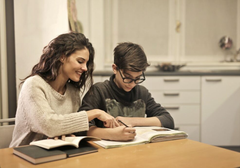 Adult helping a student with schoolwork at a desk
